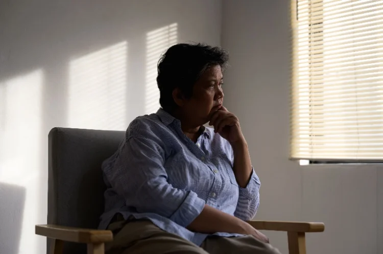 Older adult reflecting quietly near a window