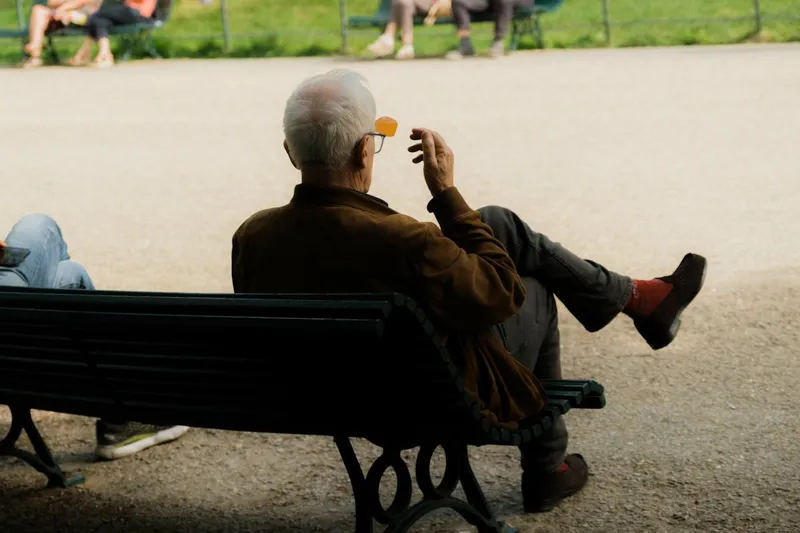 Older adult relaxing outdoors on a park bench, representing self care for caregivers and recovery from burnout